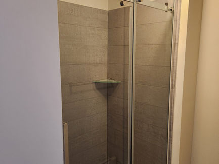 Glass shower enclosure with grey tile