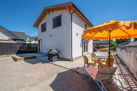 Modern white house with backyard patio, grill, and orange umbrella.