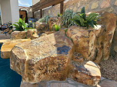 Right side angle of a faux rock waterfall, emphasizing realistic rock textures and smooth water flow.