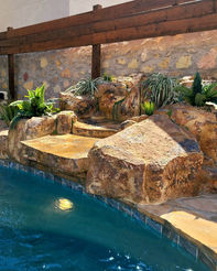 3/4 view of a faux rock waterfall, showcasing cascading water and intricate design details.
