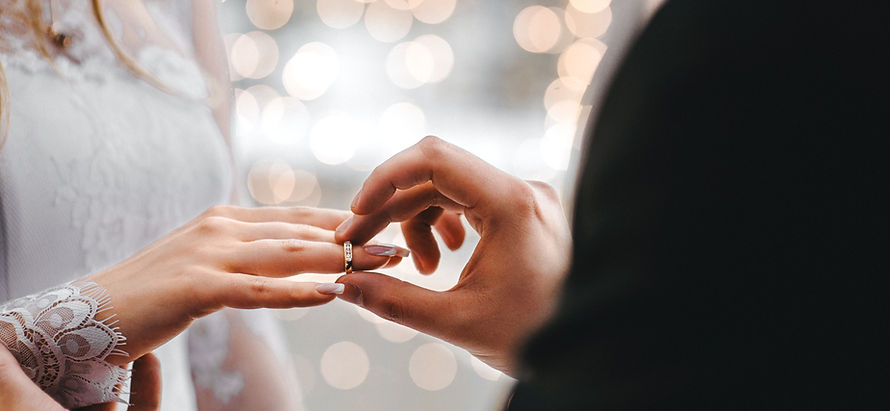 Close-up of groom placing ring on bride's finger