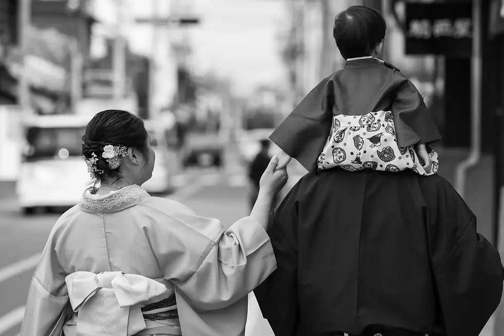 A happy family of three wearing traditional Japanese kimonos walking through the historic streets of Kawagoe.