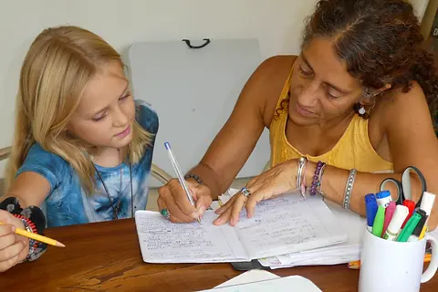 Madame Karine supporting a student with French reading and homework, reflecting her hands-on teaching experience.