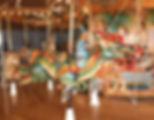 Carousel with colorful dragon, wizard, and animal figures in a wooden, decorated setting. Bright and festive atmosphere.