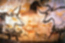 Ancient cave art depicts bulls and horses in earthy tones on a rocky wall, suggesting movement and life, capturing a prehistoric scene.