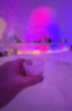 Raised shot glass made of ice inside a bar made of ice and snow.
