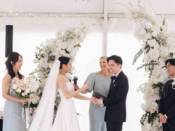 Modern indoor ceremony with bride in long veil and groom smiling under hanging greenery