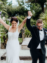 Joyful couple raising hands in celebration as they walk down the aisle after their ceremony