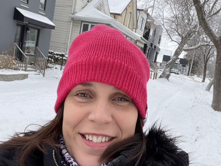 A women in a pink hat smiling in snow