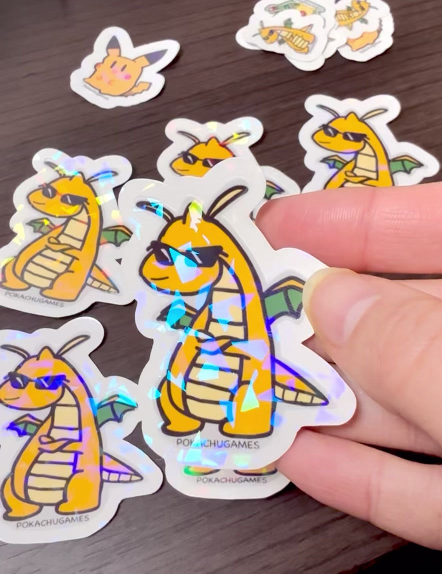 holds a small dragon sticker, showcasing its vibrant colors and intricate design against a neutral background.