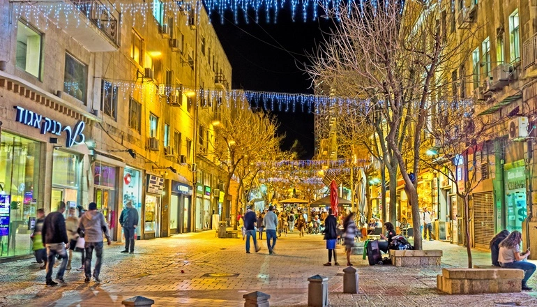 Ben Yehuda Street at night, illuminated by festive blue and white lights, showing the vibrant evening atmosphere of Jerusalem’s city center.