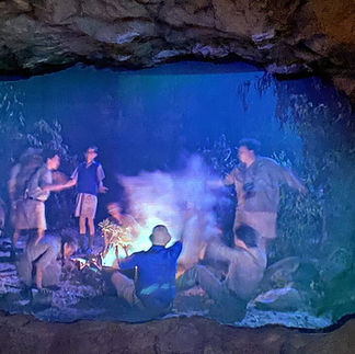 An indoor immersive exhibit at the Palmach Museum depicting a group of young soldiers gathered around a nighttime campfire.