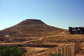Wide landscape shot of the Herodium mountain fortress with ancient Roman ruins and column bases in the foreground.