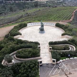 Aerial view of the 9/11 Living Memorial Cenotaph plaza. A top-down perspective showing the circular architectural design of the monument nestled within the Jerusalem forest and agricultural fields.