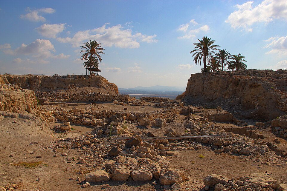 Excavated remains of the historic Canaanite city gates and palm trees on the ridge at Megiddo National Park.