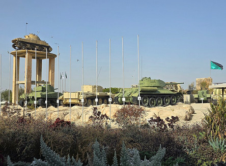 Outdoor display of historical armored vehicles and tanks on a ridge with flagpoles at the Yad LaShiryon Latrun military museum.