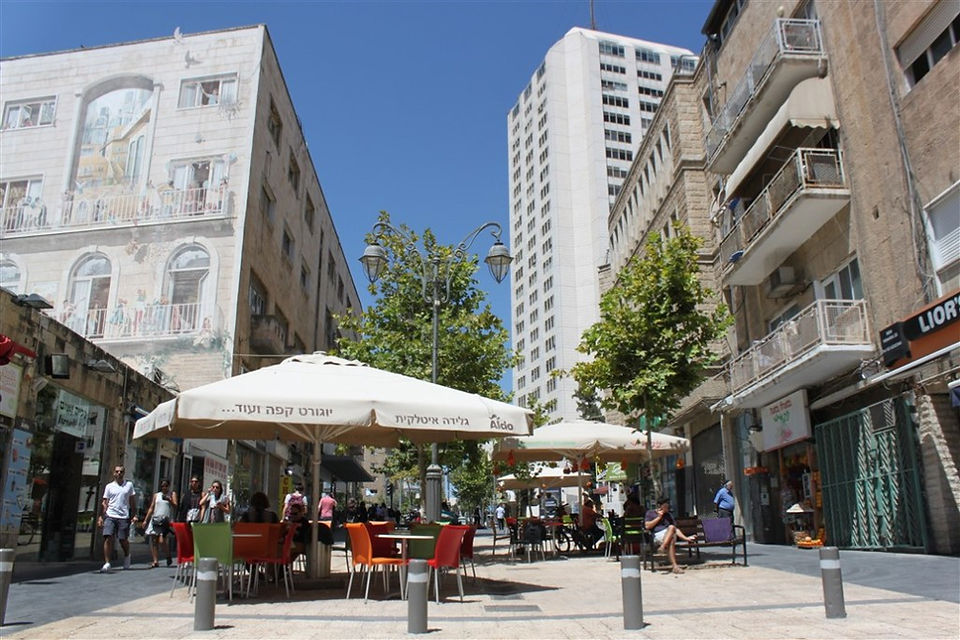 The wide pedestrian walkway of Ben Yehuda Street looking toward Zion Square, featuring modern high-rise buildings and historic Jerusalem stone.