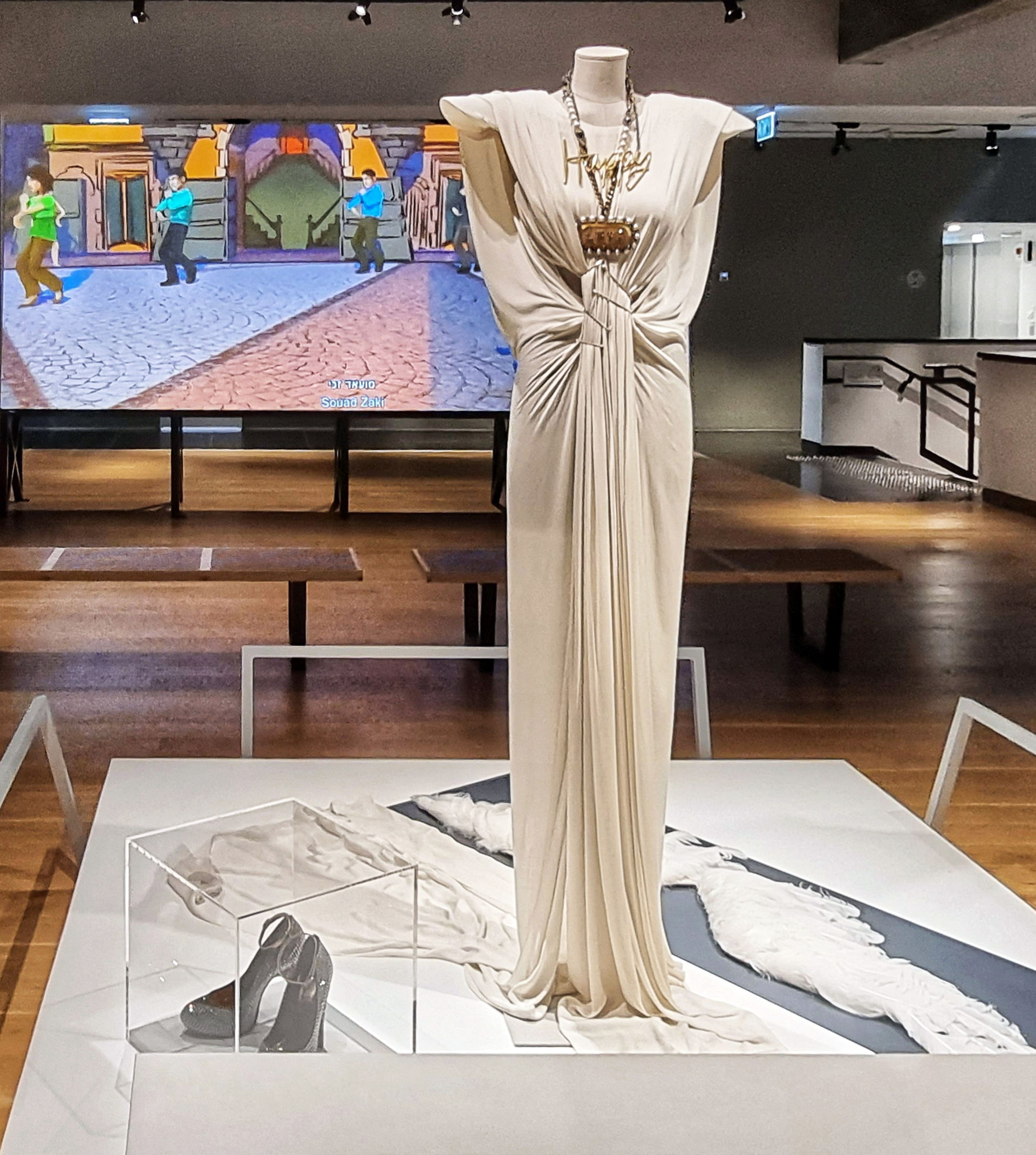 A striking white designer gown fashion exhibit displayed on a mannequin in a modern museum gallery.