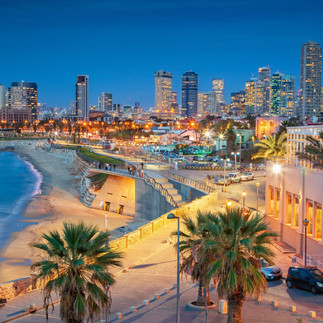 Vibrant night photography of the illuminated Tel Aviv Mediterranean coastline, sandy beach promenade, and modern 'Startup Nation' skyscrapers.