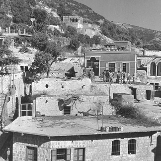 Black and white archival image of historical stone residential compounds built into the cliffs of the Galilee.