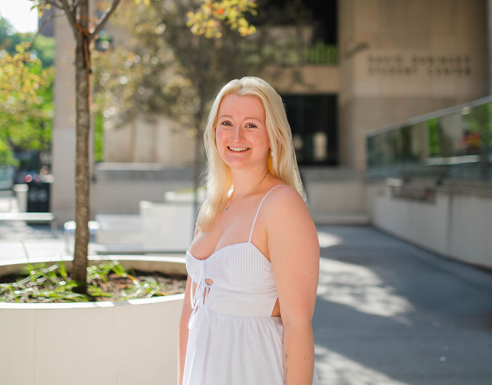White blond young woman wearing a white dress posing for a picture in a courtyard