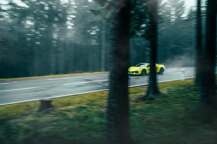 gelber Sportwagen in dunklem Nadelwald