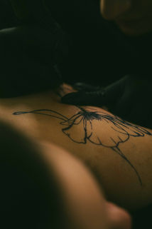 Tattoo-Künstlerin beim Stechen eines Tattoos im Licht von Neonröhren