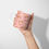 Thumbnail: Leopard Mug in Pink 11oz, leopard pattern print, with leaping leopard, pink coral background, mug held up in hand