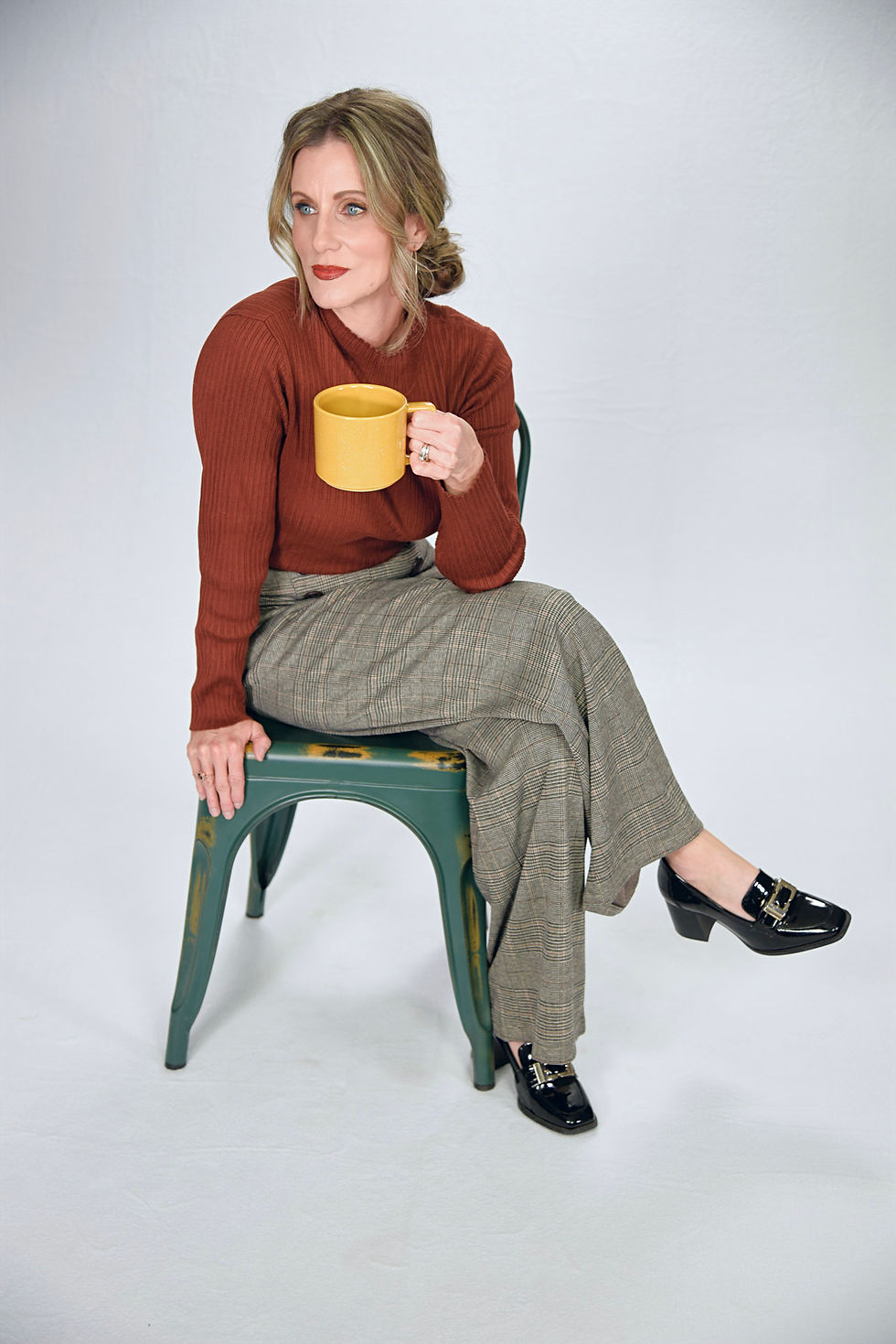 Woman named Georgette Allen sitting in a chair looking to the side and holding a yellow coffee mug