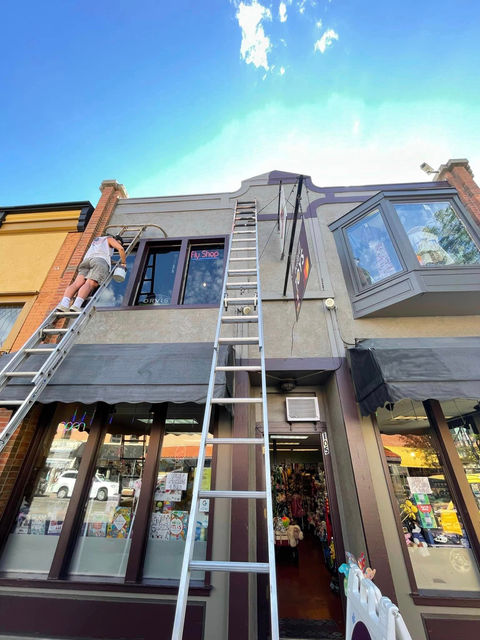 Paul Mitchell Painting providing commerical painting services on a building using ladders