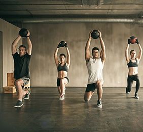 Fitness Group of men and women using medicine balls overhead