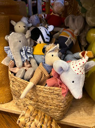A wicker basket filed with soft toy animals including and elephant and a mouse wearing a pointed birthday hat.