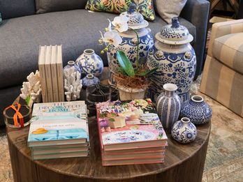 Round table with blue and white ginger jars, coral decor, and stacked books.