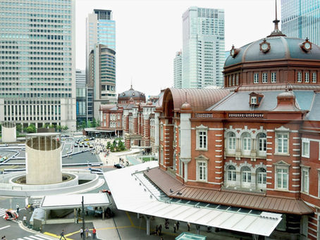 The historic red-brick building of Tokyo station against a modern city skyline.