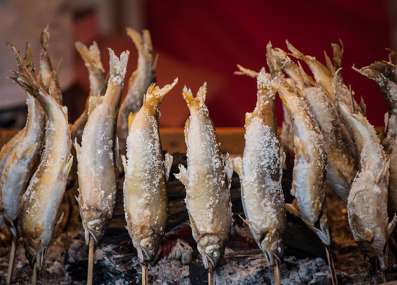 Ayu sweetfish cooking over an open grill at a summer festival in Japan.