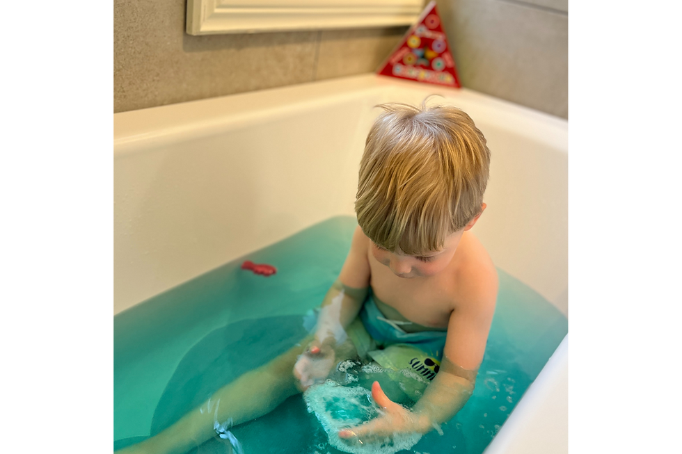 Liten gutt i badekar, blått vann, feirer bursdag og koser seg.