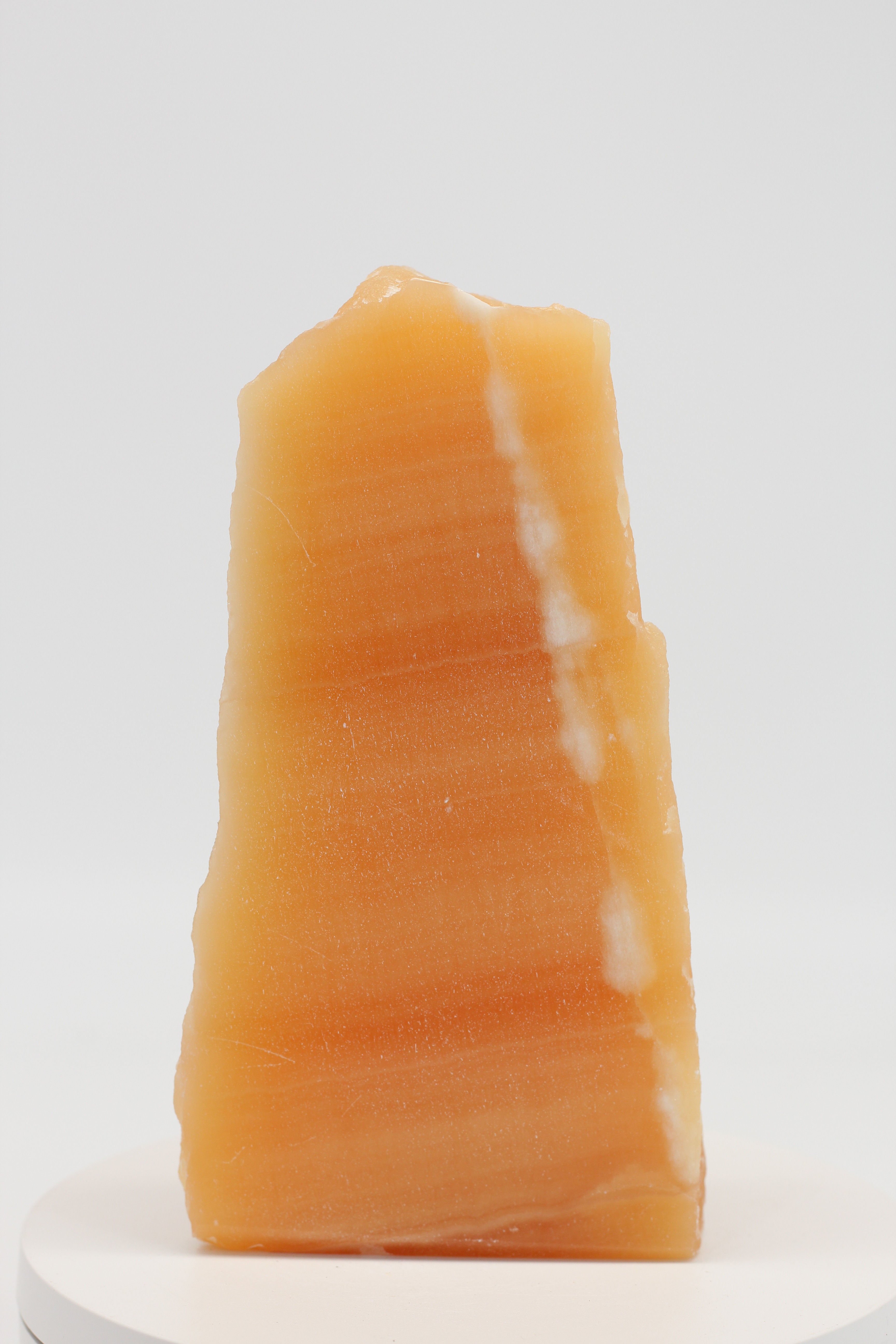 Oranje honing calciet vrijvorm met verticale witte ader op een wit plateau 15cm ORCA004