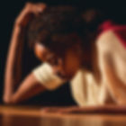 An African American woman face down on stage with a dark background.jpg
