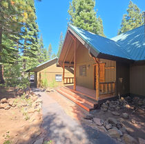 Wide view of the finished entry showing the new redwood deck, full-width redwood stair set, and concrete landing pad set in the forest setting.