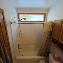 Original fiberglass tub and shower unit with dated window before the remodel