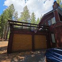 Existing weathered redwood deck over garage with low baluster railing, before replacement