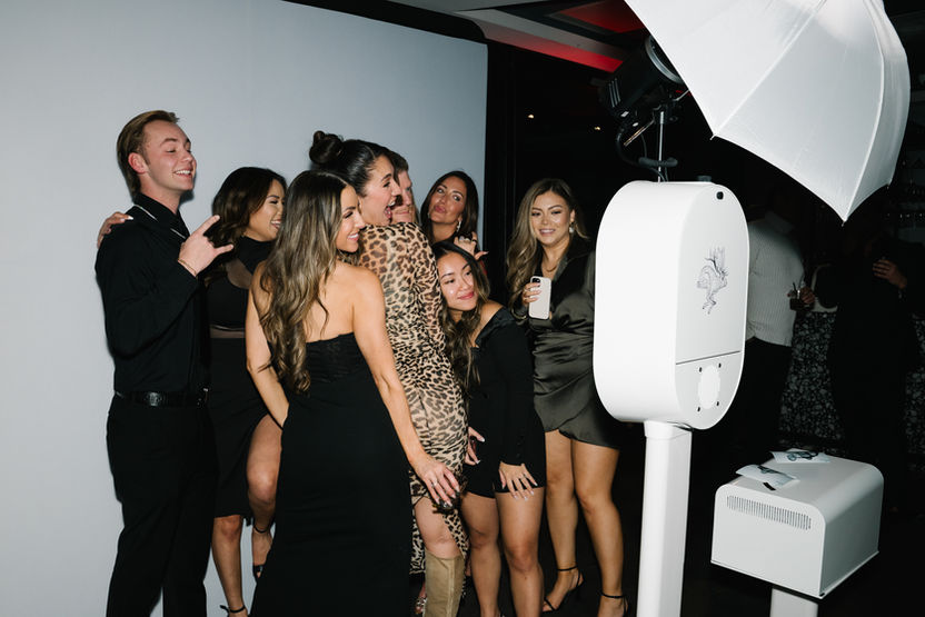 Group of guests using an open-air photo booth at an evening indoor event