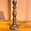 Thumbnail: Single decorative candlestick holder with an aged bronze or copper-toned finish