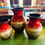Thumbnail: A set of three hand-painted ceramic or clay vases in varying sizes, featuring a vibrant red top half with distressed gold