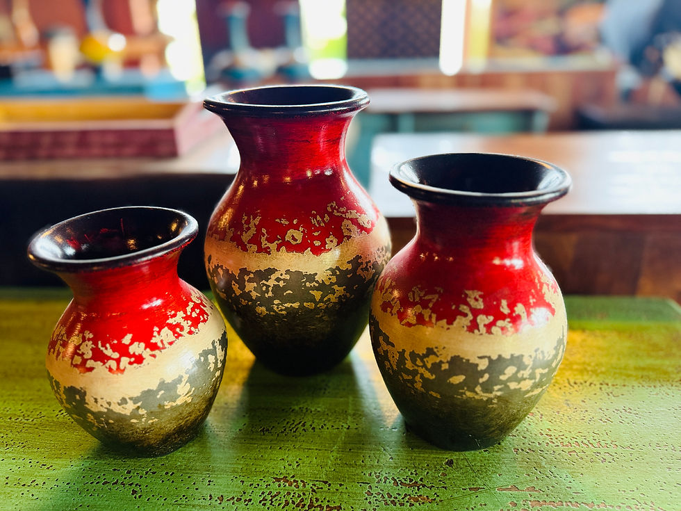 A set of three hand-painted ceramic or clay vases in varying sizes, featuring a vibrant red top half with distressed gold
