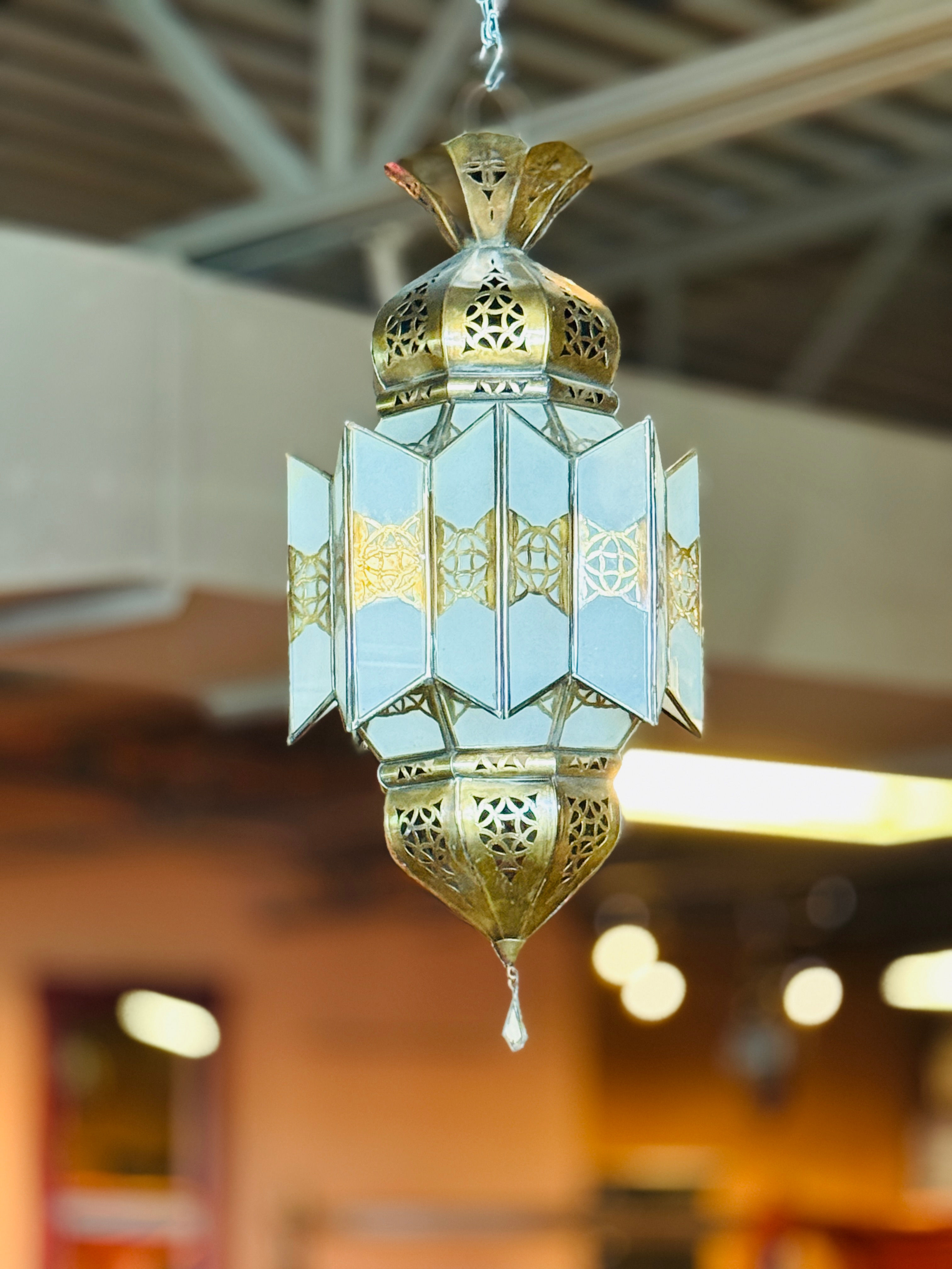 Ornate Moroccan-style hanging lantern with a light gold or brass finish, featuring frosted white glass panels