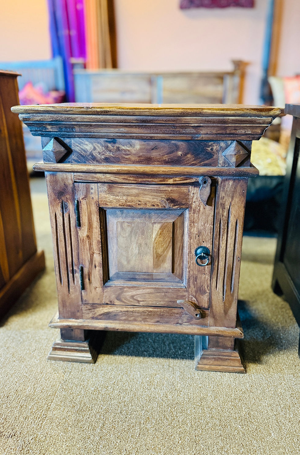 Rustic solid wood nightstand with single cabinet door and decorative accents, perfect for a bedroom.