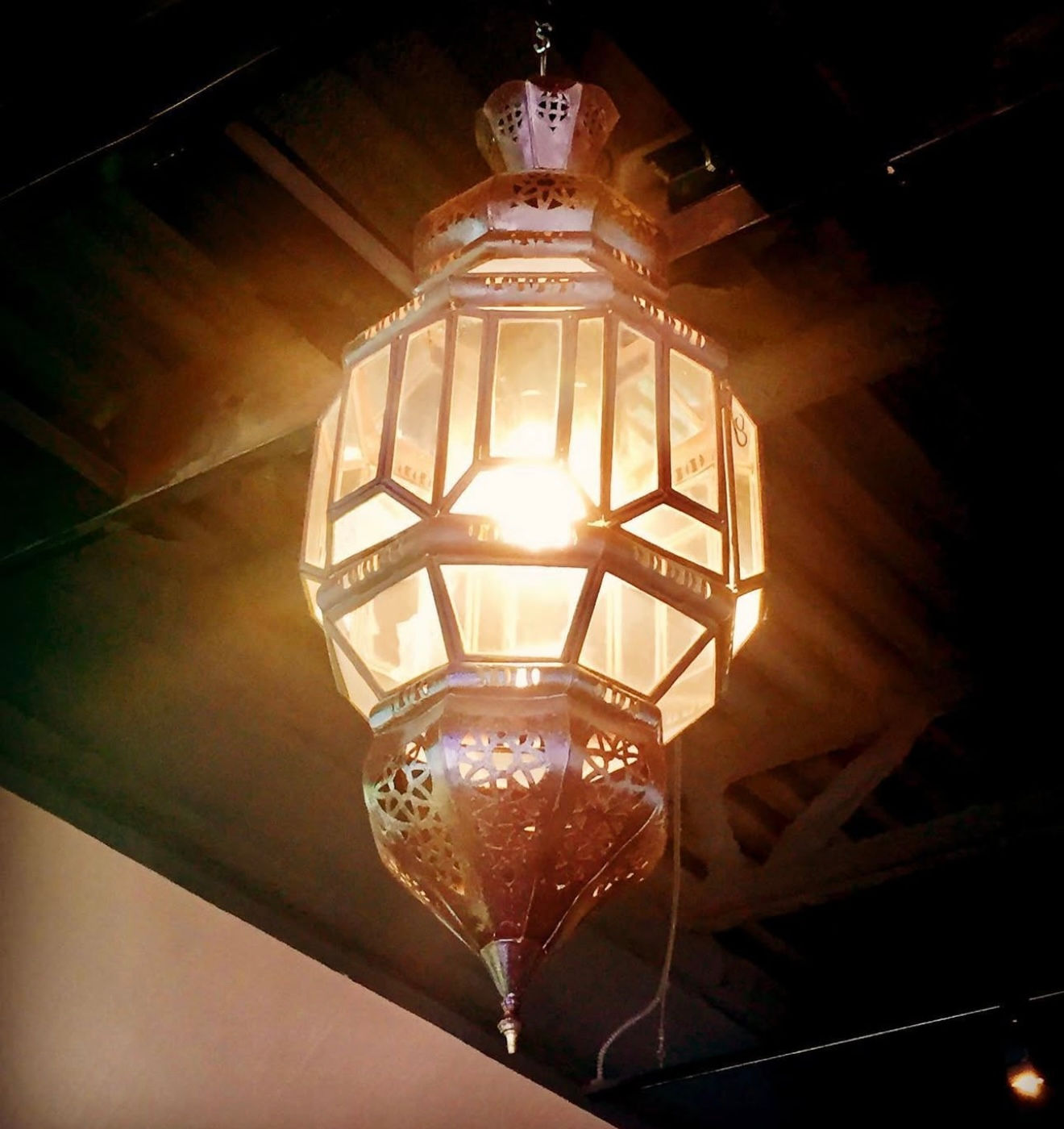 Elegant Moroccan-style pendant lantern featuring clear beveled glass panels and intricate light-colored metalwork.