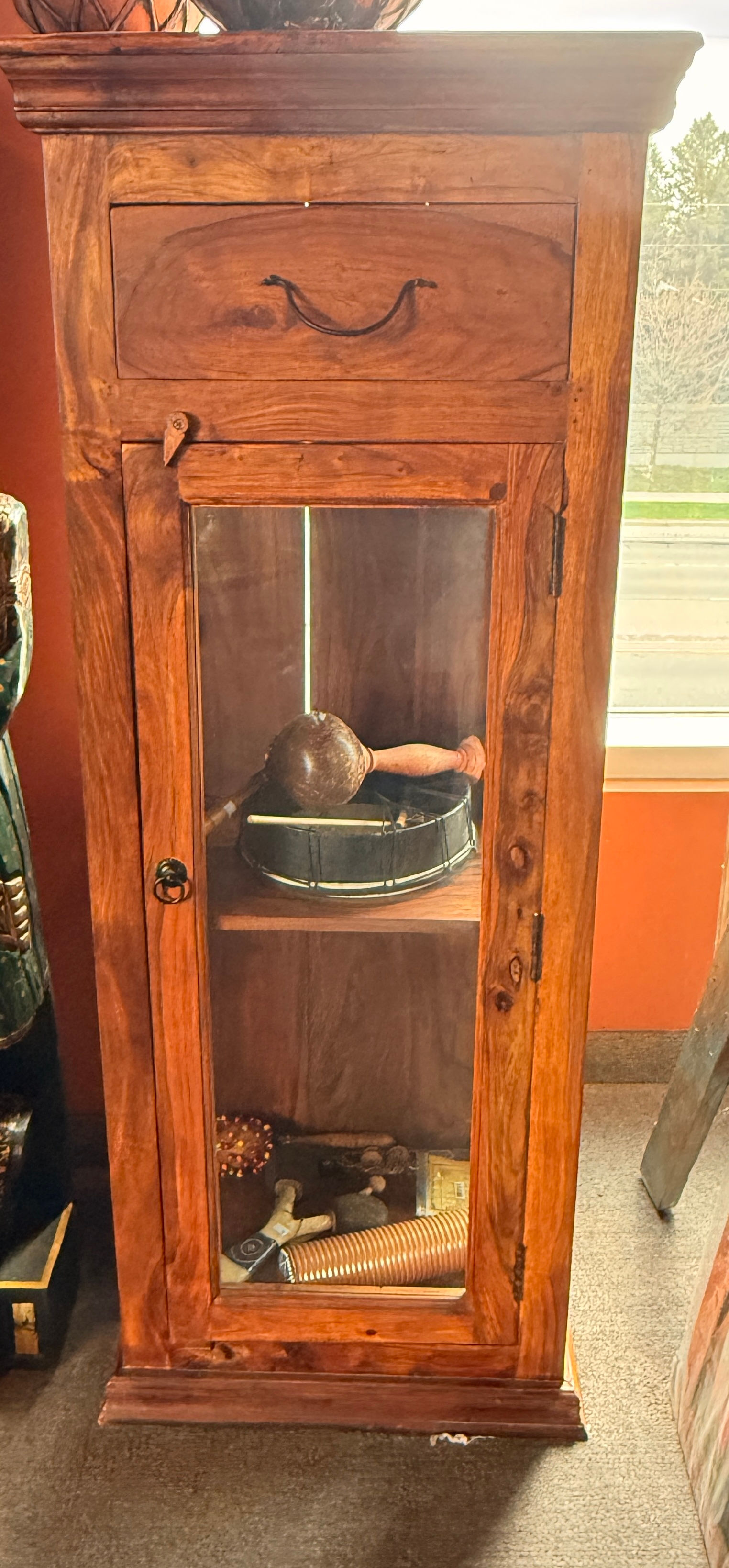 Elegant rustic wooden display cabinet with a glass door, featuring a drum and decorative items