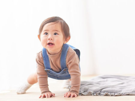 札幌の赤ちゃん整体。つかまり立ちを始めた赤ちゃんの足首やふくらはぎを優しくケアし、丸まっていた足の指がふわっと開いて地面を吸い付くように捉えられるようサポートしている臨床風景。